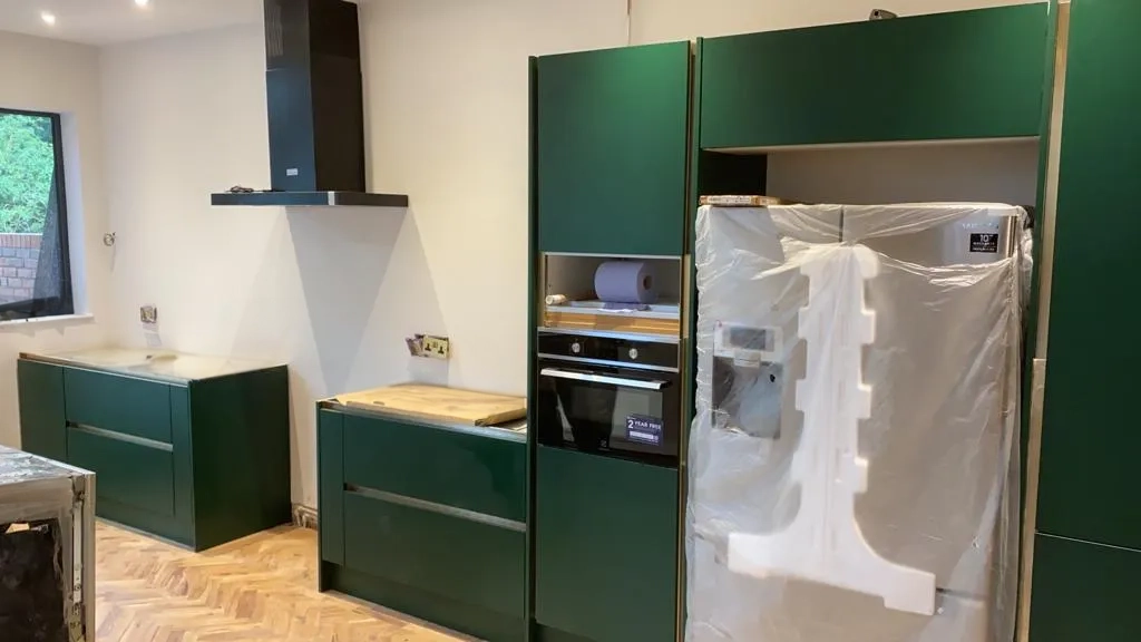 a kitchen with green cabinets and a refrigerator